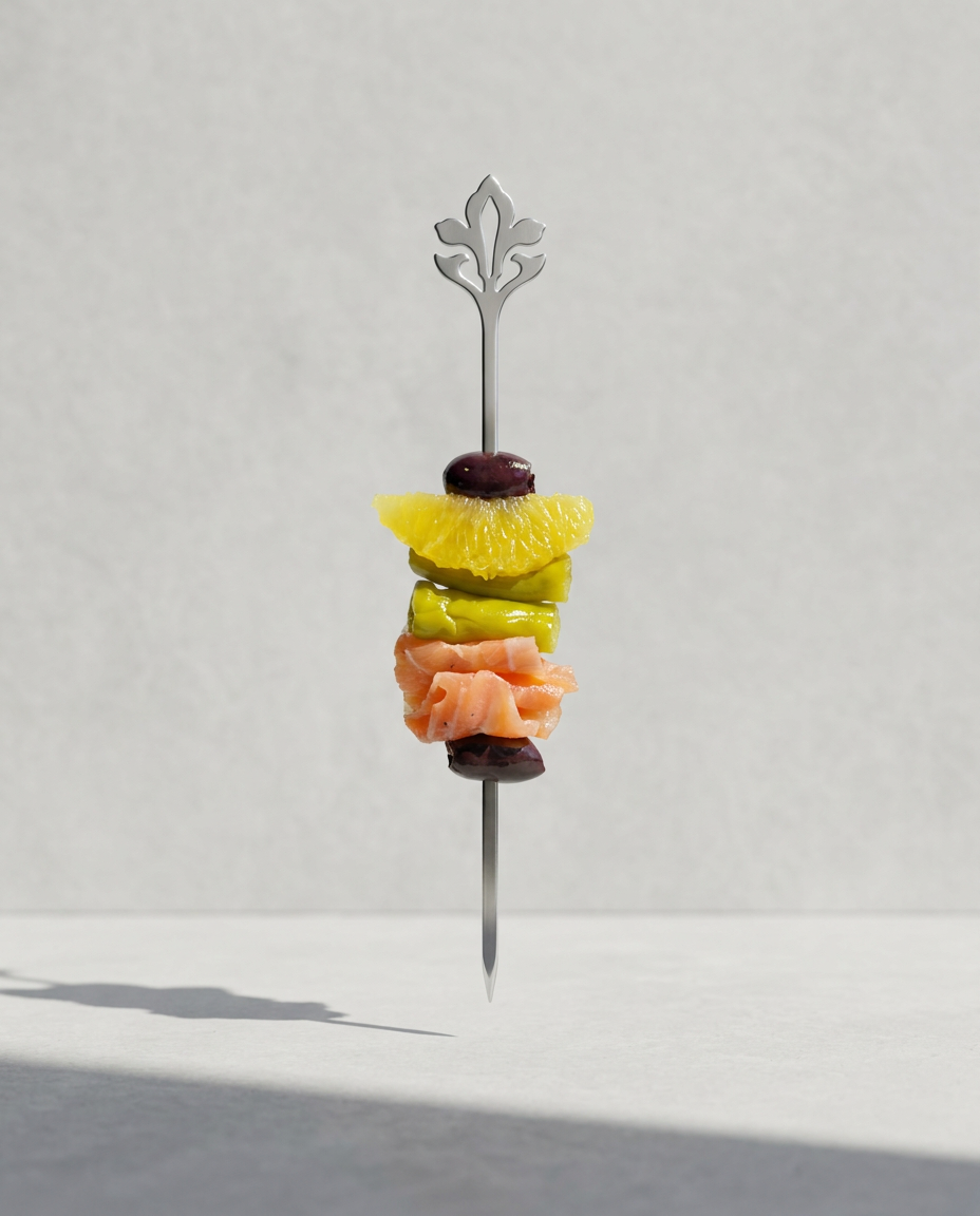 Presentación vertical de una gilda gourmet con salmón, naranja y aceituna negra en brocheta metálica con diseño de flor