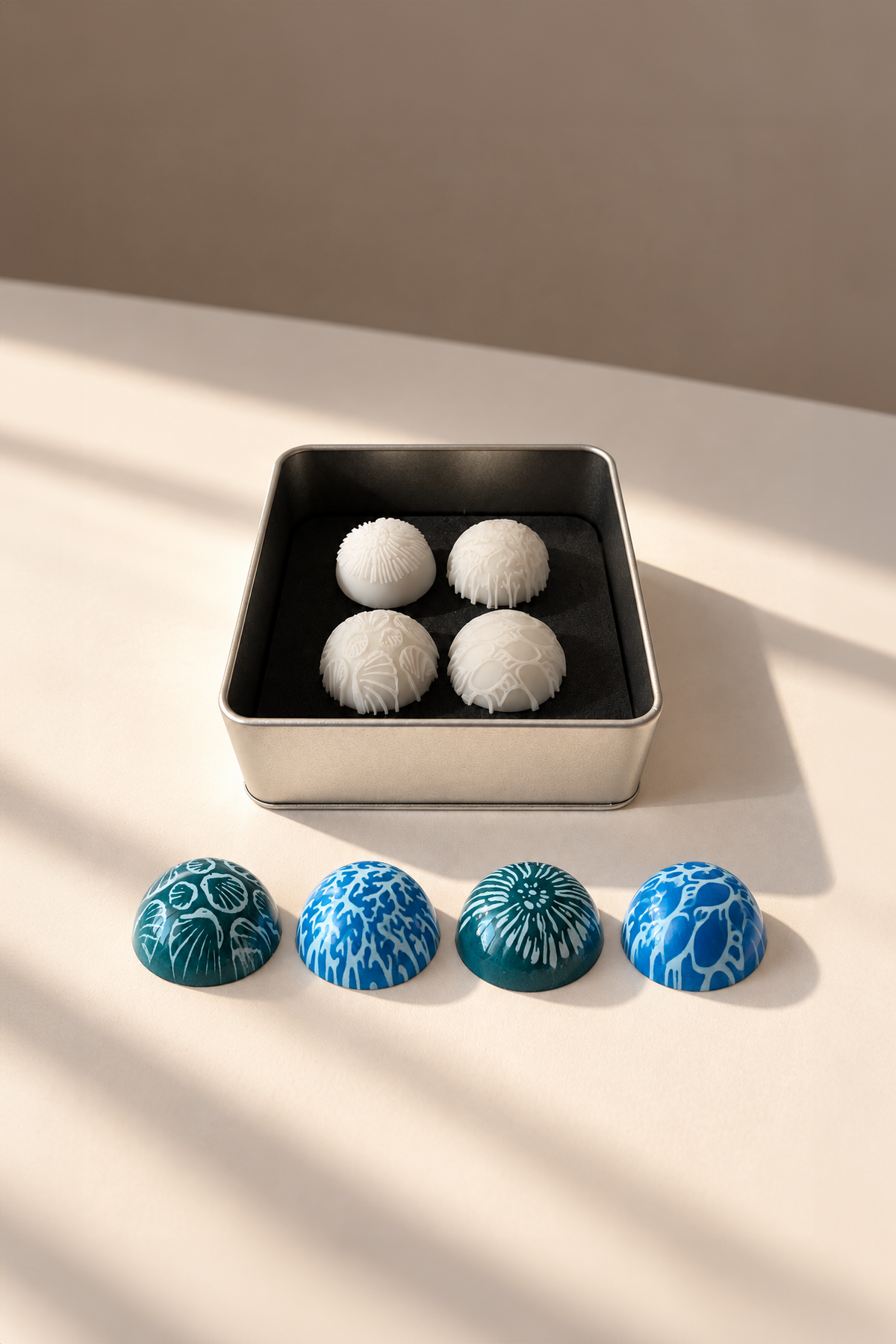 Kit de sellos de silicona Ocean para bombones junto a chocolates decorados con motivos marinos, texturas de conchas y corales en tonos azules diseñado por Andrey Dubovik 